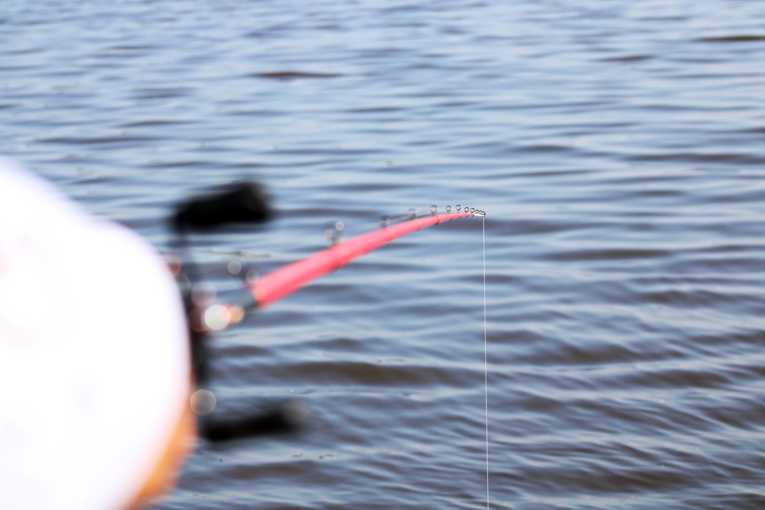 Angler casting with Mad Braid braided fishing line over a calm lake. The fishing rod bends slightly as the ultra-smooth and strong braided line extends into the water, ensuring precision and durability for an optimal fishing experience.